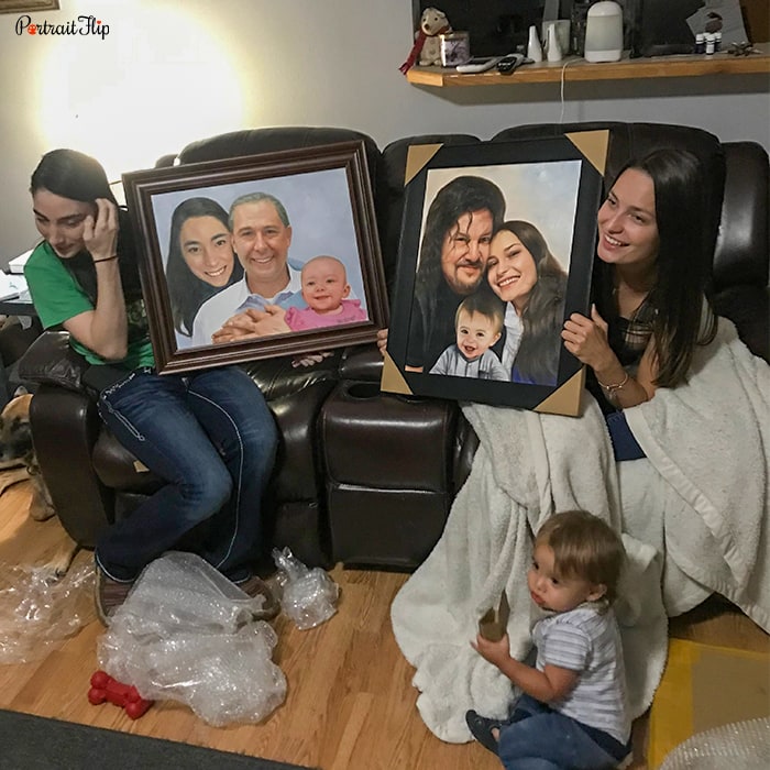 Picture of two girls holding each family portrait, where one portrait include a man, a woman and a baby boy and the other includes an old man with a baby and a girl behind his back