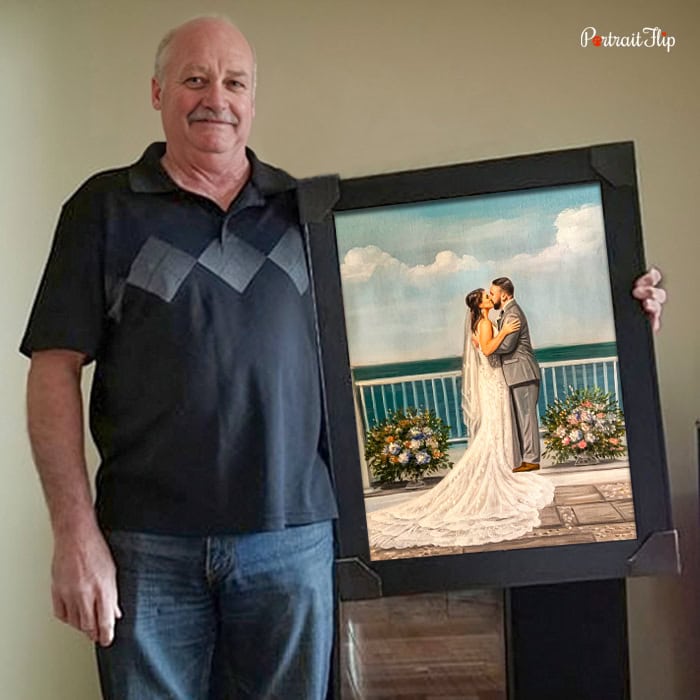 Man holding a framed wedding portrait painting