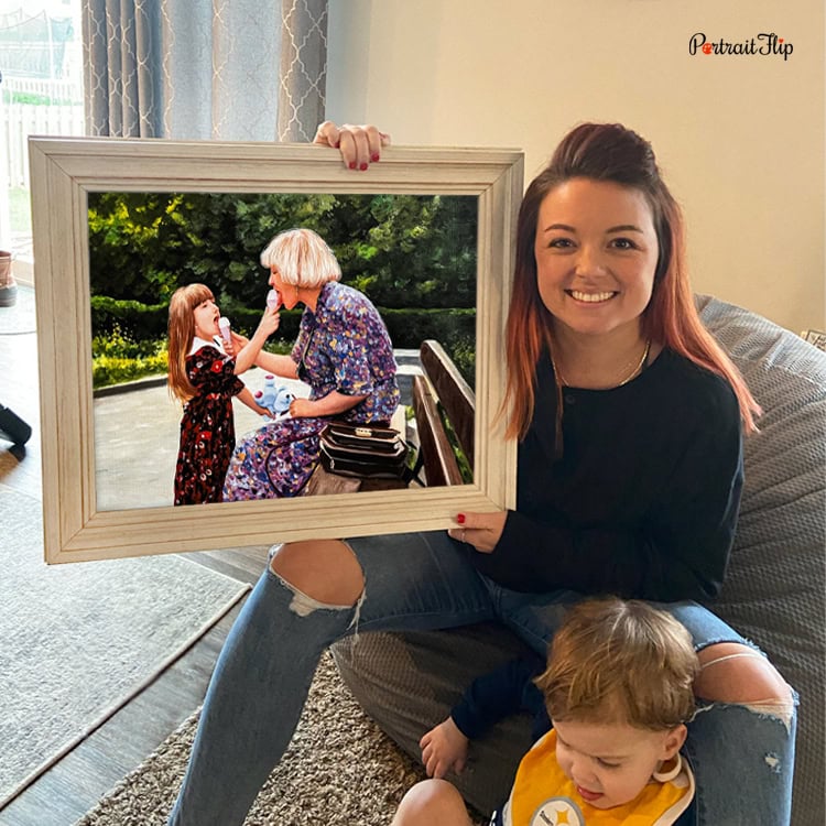 Woman holding a framed custom impasto painting of grandmother and granddaughter